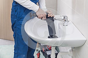 Professional plumber unclogging a sink