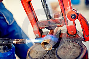 Professional plumber welding copper and fittings with blowtorch photo