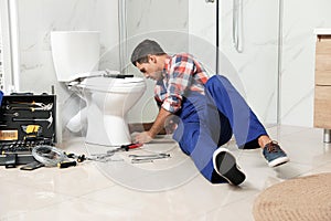 Professional plumber working with toilet bowl