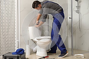 Professional plumber working with toilet bowl