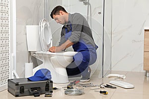 Professional plumber working with toilet bowl