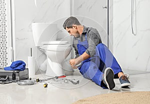Professional plumber working with toilet bowl