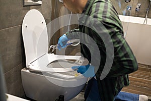 Professional plumber working with toilet bowl in bathroom