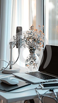 Professional podcast studio setup with a microphone and laptop on a clean white desk