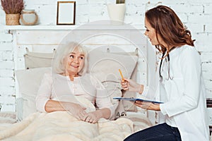 Professional positive female doctor examinig her patient at home