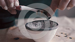 Professional potter decorating and painting a dish after she has baked it in the kiln