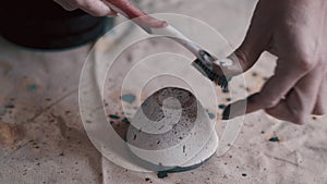 Professional potter decorating and painting a dish after she has baked it in the kiln