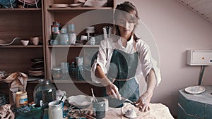 Professional potter decorating and painting a dish after she has baked it in the kiln