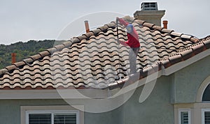 Professional pressure-washing a tile roof on a home