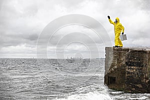 Professional in protective suit standing with silver case on concrete shelter