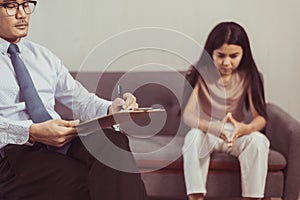 Professional psychologist talking with asian woman patient and writing notes,Therapist conducting a consultation and counseling to