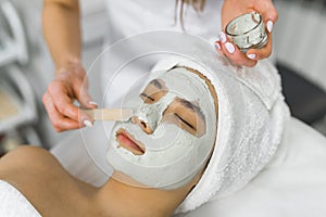 professional putting facial mask for her client at the beauty center, closeup side view beauty treatment