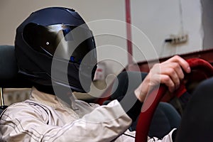 A professional racer in a black helmet and a white homologated suit sits in the sports seat of a car for drifting and racing photo