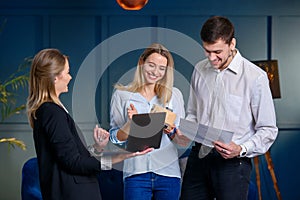 Professional realtor, designer showing plan of future design on the laptop to the couple of clients.