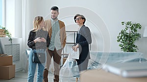 Professional realtor talking to customers man and woman showing new apartment