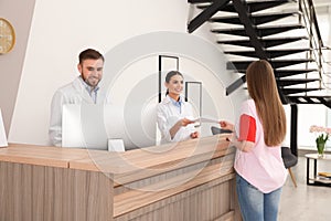 Professional receptionists working with patient at desk