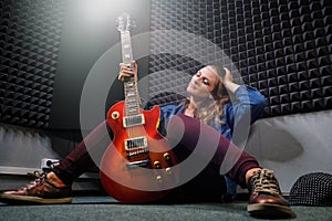 Professional recording Studio music recording. Musician woman sitting with a red electric guitar in the recording Studio. Girl