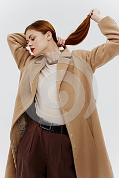 Professional redhead model posing on a white background in a coat. Advertising for brands showrooms catalog of clothing