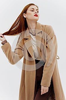 Professional redhead model posing on a white background in a coat. Advertising for brands showrooms catalog of clothing