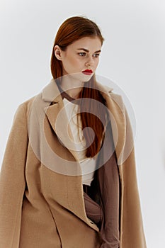 Professional redhead model posing on a white background in a coat. Advertising for brands showrooms catalog of clothing