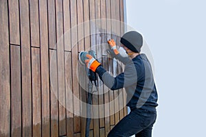 Professional renovation of hardwood cladding, man sanding, removing oxidation and dirt cleaning wood siding with an orbital power