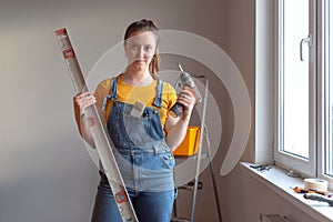 Professional repairwoman doing a home renovation. Female posing and holding a drill and level.