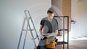 Professional repairwoman drawing up a room plan making notes in the blueprint