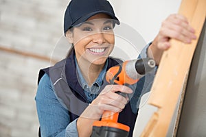 Professional repairwoman holding electrical drill indoors