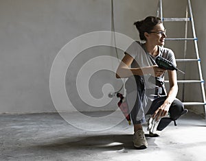 Professional repairwoman posing and holding a drill