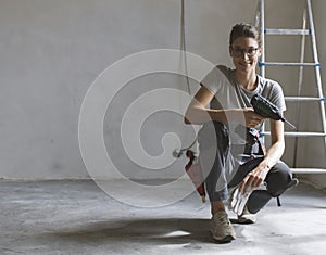 Professional repairwoman posing and holding a drill