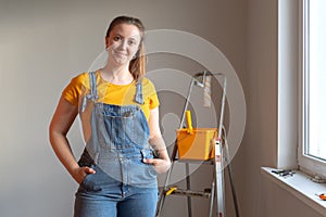 Professional repairwoman posing with tool on ladder doing a home renovation. DIY repair.