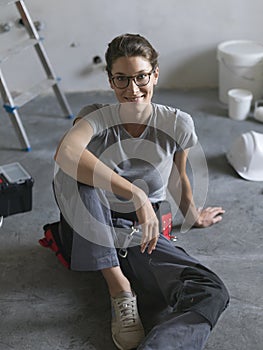 Professional repairwoman sitting on the floor and posing