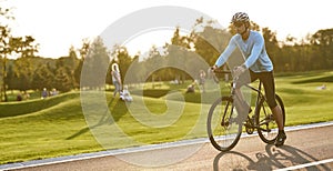 Professional road bicycle racer training outdoors. Young athletic man in sportswear and protective helmet standing with