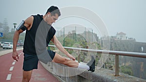 Professional runner doing exercise on street. Focused athlete warming up legs