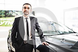 Professional salesman smiling in front of a new car