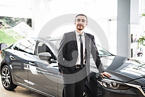 Professional salesman smiling in front of a new car