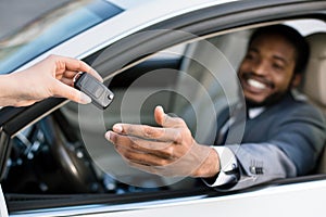 Professional salesperson giving keys to new car owner