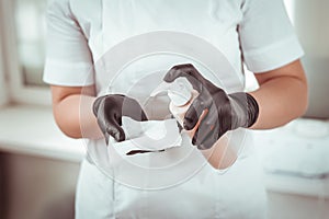 Professional salon worker in rubber gloves spraying antiseptic