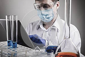 Professional scientist holding a test tube and tablet while making a research