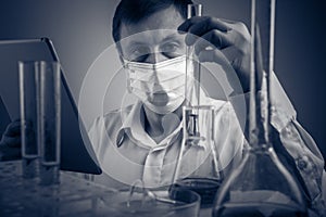 Professional scientist holding a test tube and tablet while making a research