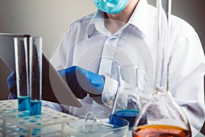 Professional scientist holding a test tube and tablet while making a research