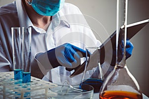 Professional scientist holding a test tube and tablet while making a research