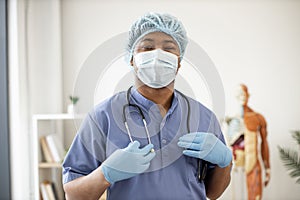 Professional in scrubs and mask standing in consulting room