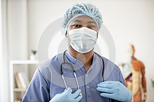 Professional in scrubs and mask standing in consulting room