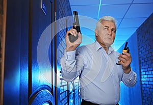 Professional security guard with gun and portable radio set in hallway