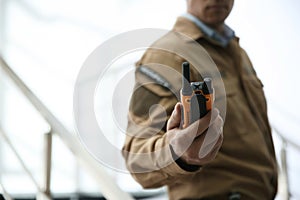 Professional security guard with portable radio set, closeup