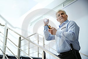Professional security guard with portable radio set and flashlight on stairs