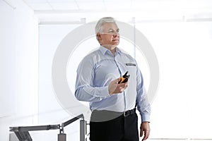 Professional security guard with portable radio set indoors