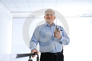 Professional security guard with portable radio set indoors