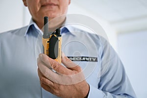 Professional security guard with portable radio set indoors